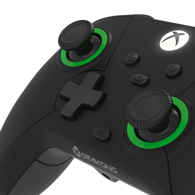 Black gaming controller with green accents on a white background